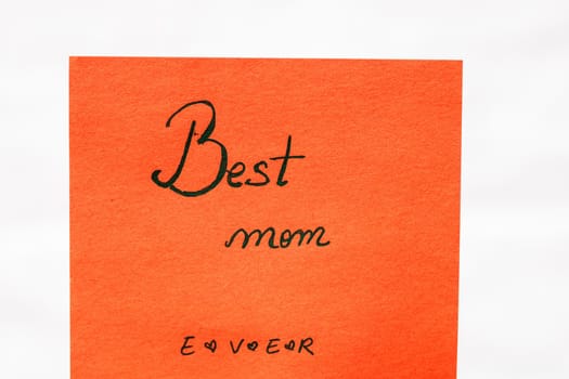 Best mom ever handwriting text close up isolated on orange paper with copy space. Writing text on memo post reminder