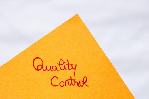 Quality control  handwriting text close up isolated on orange paper with copy space.