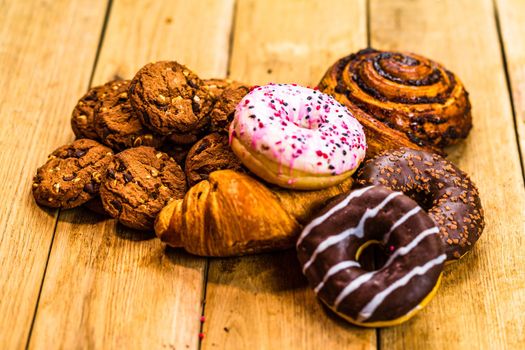 Colorful donuts on wooden table. Sweet icing sugar food with glazed sprinkles, doughnut with chocolate frosting. Top view with copy space