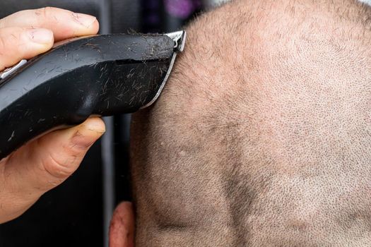 Man shaving or trimming his hair using a hair clipper