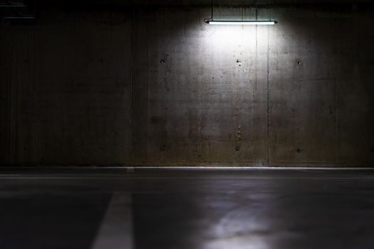 Empty parking lot with overhead dim light, underground parking garage.