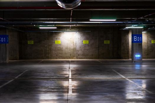 Empty parking lot with overhead dim light, underground parking garage.