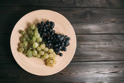 grapes in a plate on a wooden table top view fruits. High quality photo
