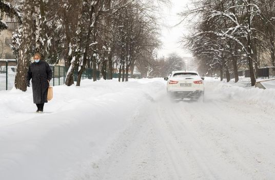 Lutsk, Ukraine - February 12,2020: People on street after snow storm. City street after blizzard. Record-breaking amounts of snow. Uncleaned slippery roads and sidewalk in winter. Cars in snowdrift
