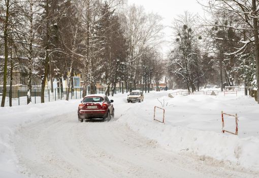 Lutsk, Ukraine - February 12,2020: Stuck car in snow and ice. City street after blizzard. Buried vehicle in snowdrift. Parking in winter after snowfall. Uncleaned road. Record-breaking amounts of snow