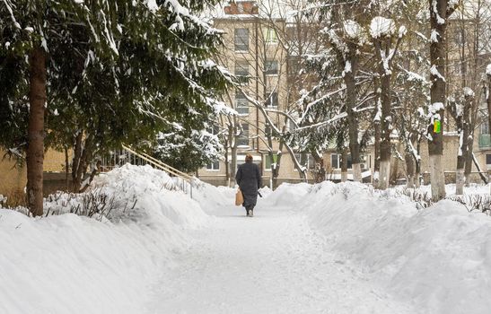 Lutsk, Ukraine - February 12,2020: People on street after snow storm. City street after blizzard. Record-breaking amounts of snow. Uncleaned slippery roads and sidewalk in winter. Cars in snowdrift