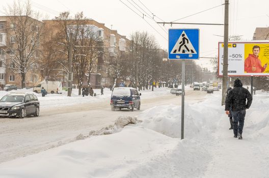 Lutsk, Ukraine - February 12,2020: People on street after snow storm. City street after blizzard. Record-breaking amounts of snow. Uncleaned slippery roads and sidewalk in winter. Cars in snowdrift