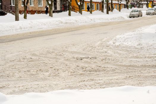 Lutsk, Ukraine - February 12,2020: Uncleaned slippery roads and sidewalk in winter. Cars in snowdrift. People on street after snow storm. City street after blizzard. Record-breaking amounts of snow