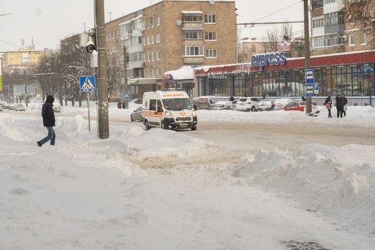 Lutsk, Ukraine - February 12,2020: Uncleaned slippery roads and sidewalk in winter. Cars in snowdrift. People on street after snow storm. City street after blizzard. Record-breaking amounts of snow