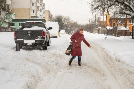 Lutsk, Ukraine - February 12,2020: Uncleaned slippery roads and sidewalk in winter. Cars in snowdrift. People on street after snow storm. City street after blizzard. Record-breaking amounts of snow