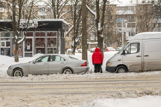 Lutsk, Ukraine - February 12,2020: Stuck car in snow and ice. City street after blizzard. Buried vehicle in snowdrift. Parking in winter after snowfall. Uncleaned road. Record-breaking amounts of snow