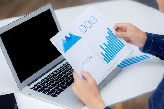 Hand of young business man looking document data graph and chart paper, marketing and investment, report of statistics profit for financial, economic and growth of finance, management and planning.