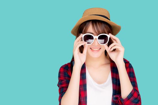 Beautiful portrait young asian woman wear hat and holding sunglasses smiling confident enjoy journey summer trip in vacation isolated on blue background, tourist asia girl cheerful with travel.