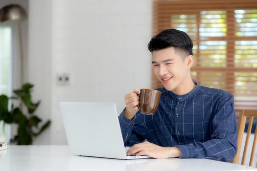 Young business man working from home with laptop computer on desk, freelance male sitting stay home using notebook for communication and relax on table, entrepreneur in startup business, new normal.