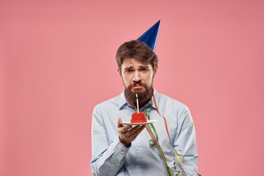 Birthday of a man with a cake and with a candle on a pink background. High quality photo