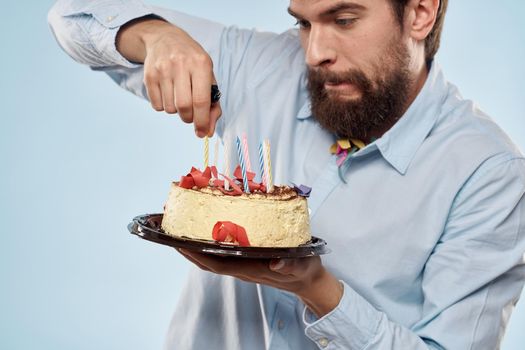 Man with a plate of cake and a festive candle blue background cap corporate party. High quality photo
