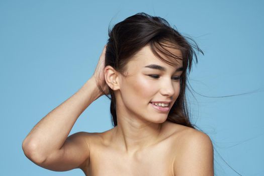 Pretty woman naked shoulders hair care close-up bank blue background. High quality photo