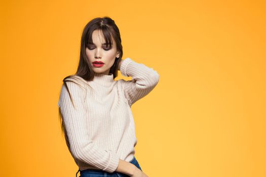Cute brunette makeup red lips fashionable clothes yellow background. High quality photo