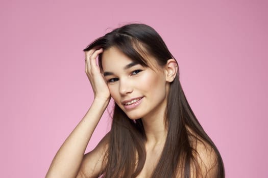 brunette bare shoulders clear skin body care pink background. High quality photo
