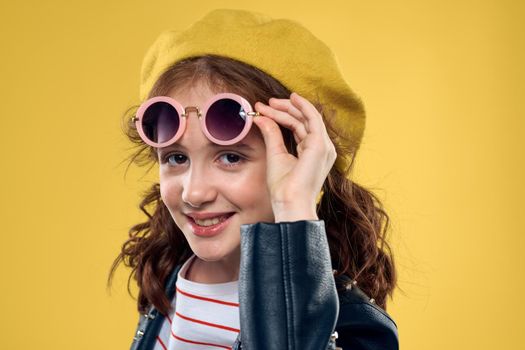 Girl in a yellow hat dark glasses fashionable clothes studio lifestyle childhood. High quality photo