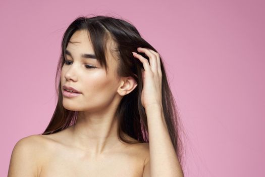 Pretty brunette naked shoulders clear skin pink background. High quality photo