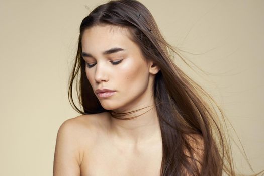 Pretty woman naked shoulders cosmetics clean skin hair care beige background. High quality photo