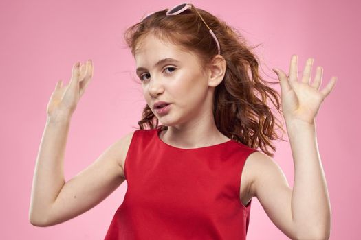 Cheerful little girl childhood dark glasses red dress lifestyle pink background. High quality photo