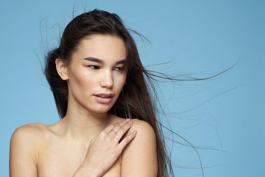 pretty brunette naked shoulders long hair skin care blue background. High quality photo