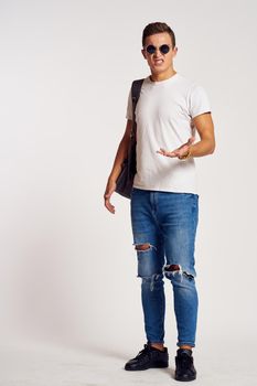 a man with a backpack on his back in jeans t-shirt full length sneakers and glasses on his face. High quality photo