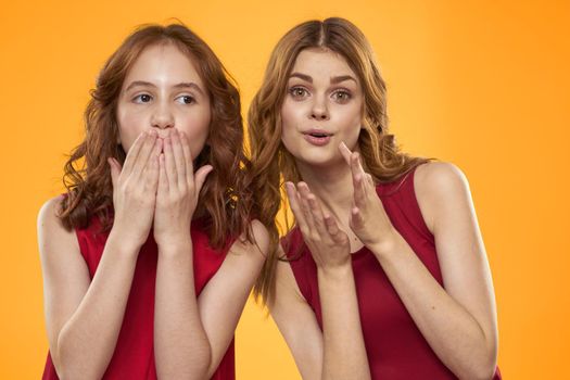 Mom and daughter in red dresses entertainment lifestyle yellow background. High quality photo