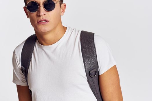 handsome man with backpack on his back gesturing with his hands in a t-shirt and wearing glasses Copy Space portrait cropped view