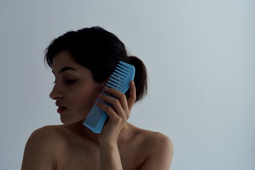 Pretty brunette combs hair bare shoulders shower grooming. High quality photo