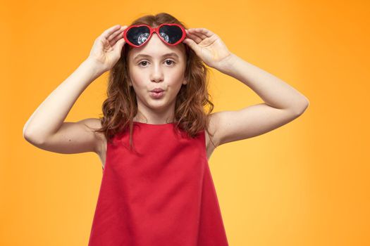 Cheerful little girl red dress curly hair yellow background childhood. High quality photo
