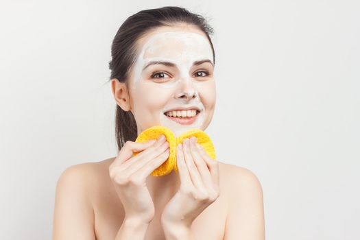 emotional woman with sponges in hands cream mask on face cropped view. High quality photo