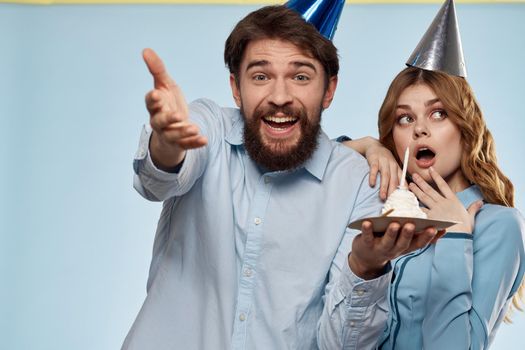 Cheerful man and woman with cake in a plate corporate party blue background. High quality photo