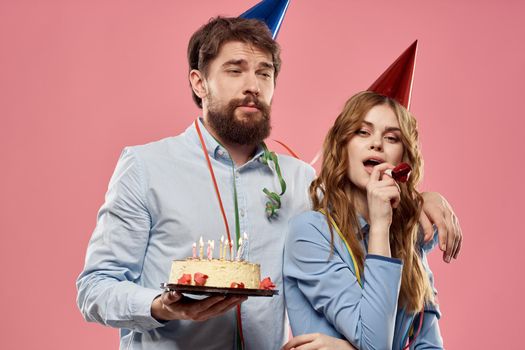 Party man and woman with cake on pink background corporate birthday. High quality photo