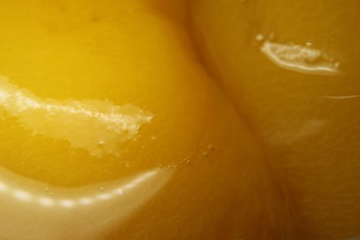 Closeup view with selective focus of yellow peaches slices. Canned peaches halves sprinkled with syrup.