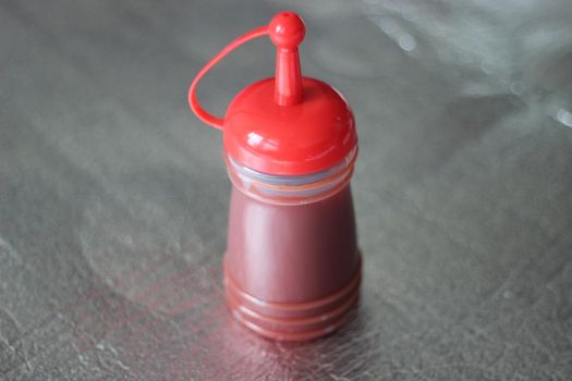 Closeup of red plastic ketchup bottle placed on floor