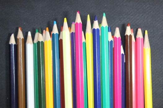 Close-up view of bright colored multicolor pencils on black background