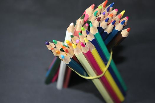 Close-up view of bright colored multicolor pencils on black background