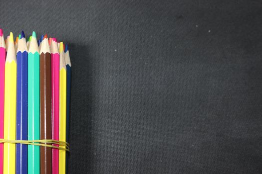 Close-up view of bright colored multicolor pencils on black background