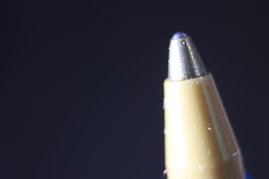 Macro photo of ballpoint pen tip with dark grey background. Extreme macro image of metal ballpoint pen on grey background.