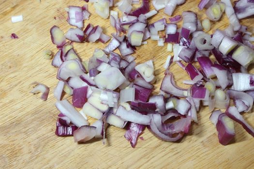 Chopped white onion with sharp knife on wooden cutting board. High angle top view of chopped onions pieces