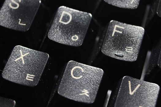 Closeup of laptop computer keyboard black keys with white letters and numbers. Black keys with white characters.