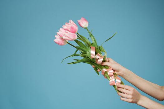 A bouquet of flowers in the hands of a holiday romance gift blue background. High quality photo