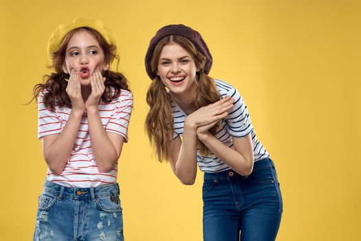 funny mom and daughter wearing hats fashion fun joy family yellow background. High quality photo