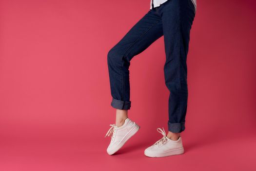 Womens feet white sneakers fashion street style pink background. High quality photo