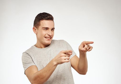 handsome man in a t-shirt gesturing with his hands emotions studio light background. High quality photo