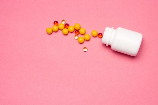 Open jar with pills on pink background coldspace top view. High quality photo