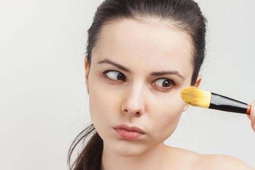 woman naked shoulders brushing cream on face cropped view. High quality photo